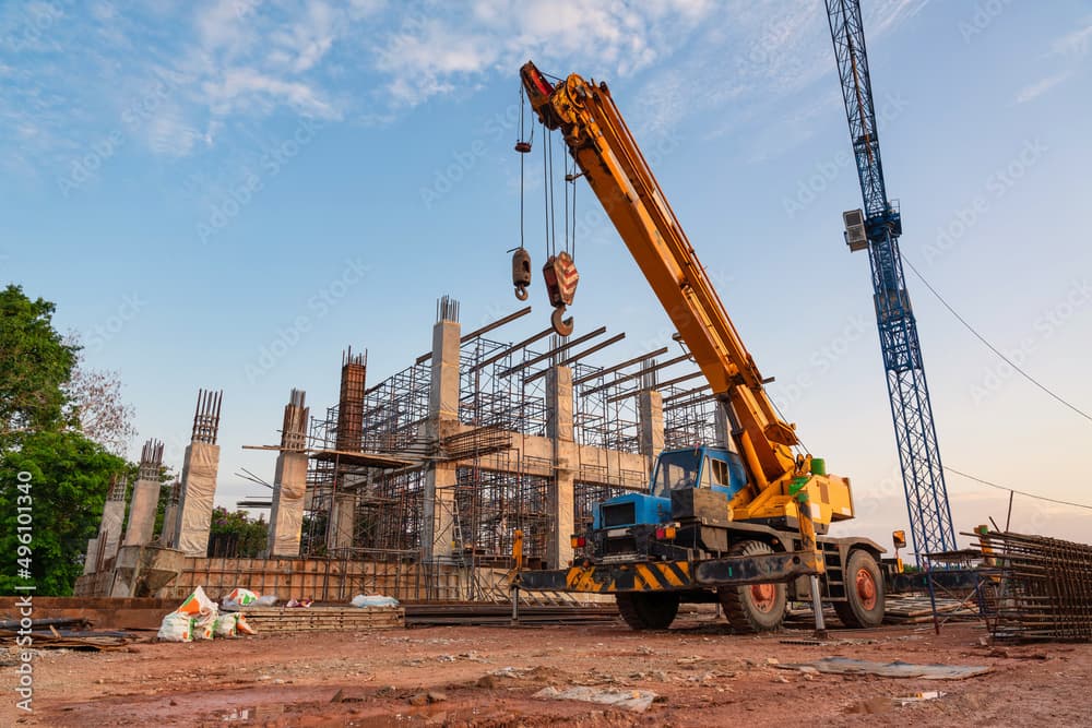Heavy crane lifting steel beams at a construction site in Telangana